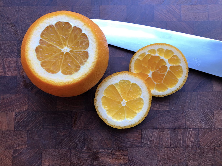 Image of Remove the top and bottom from the oranges with a sharp knife.