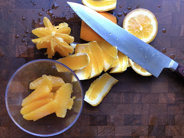 Image of Put the cut segments in a bowl or push them to the side of your cutting board. Squeeze the peels and core of the orange to extract any juice and place this in another bowl.
