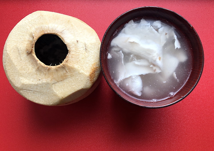 Image of Drain the water inside into a bowl and using a spoon scoop the flesh from the inside of the coconut and add it to the bowl as well.