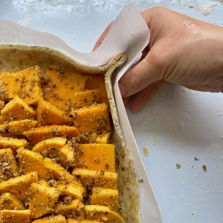 Image of Using the paper for support, stand the sides of the galette up, bending at the scored mark, and pinch the corners together to seal.