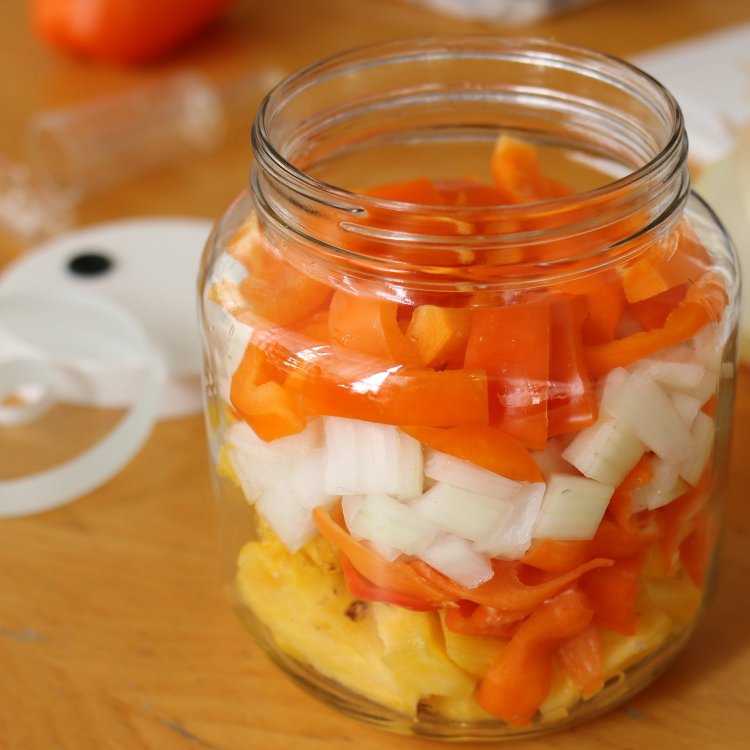 Image of Pack pineapple, peppers and onion into fermentation jar.