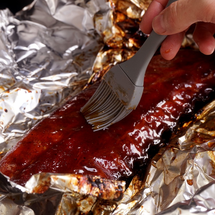Image of After an hour, unwrap the ribs and coat with the apple juice reduction. Let the sauce set for 10-20mins then remove from the smoker.