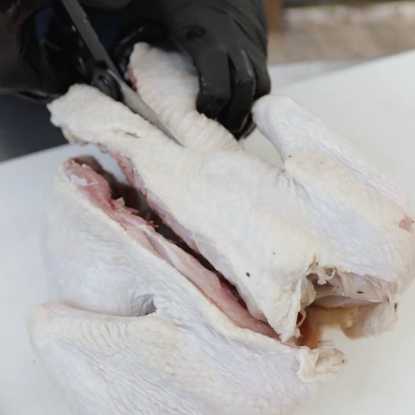 Image of Flip over turkey and remove the backbone by cutting along...