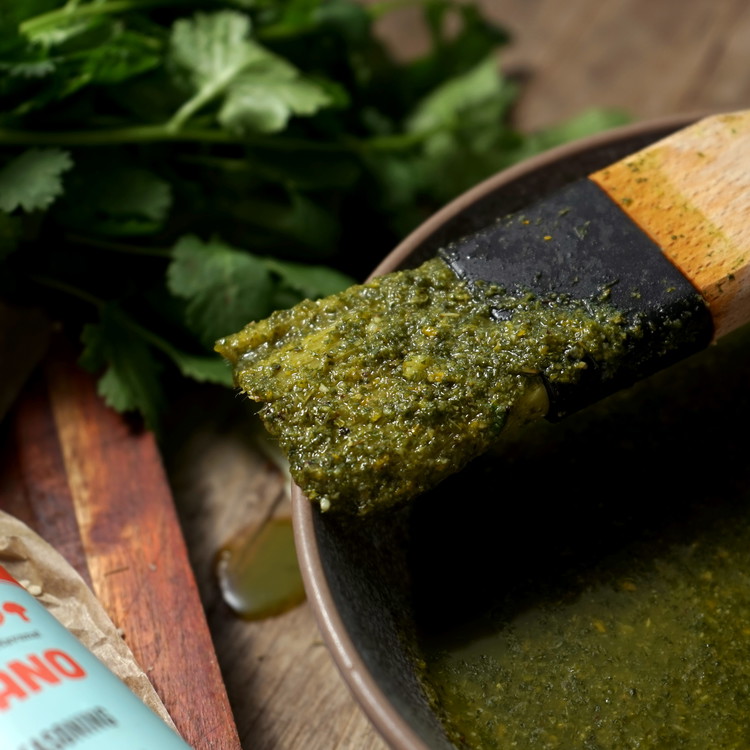Image of While the pork is cooking prepare the Mojo sauce. place olive oil, orange zest, juice, lime juice, cilantro, mint, garlic, oregano, cumin and brown sugar into a blender and blitz until combined. 