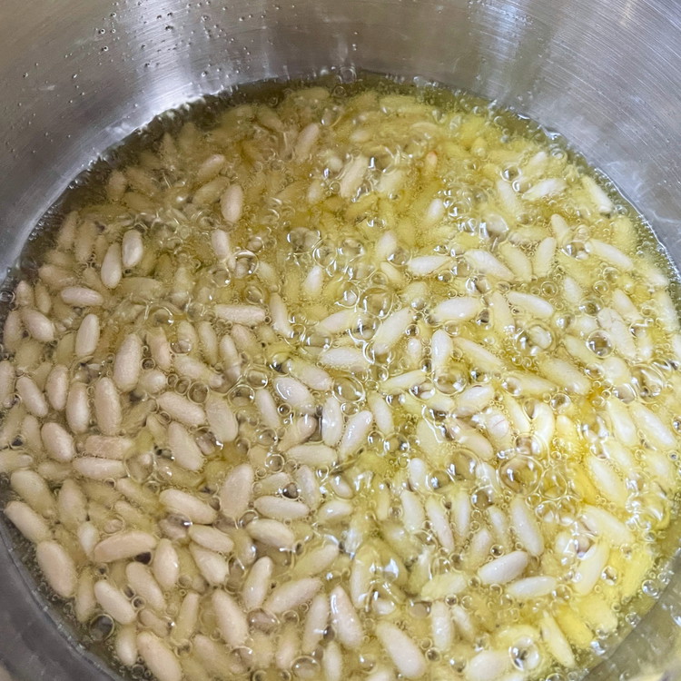 Image of In a small saucepan combine the pine nuts and olive oil. Place over medium low heat and cook, stirring occasionally. While the pine nuts are cooking, add the pasha and a pinch of salt to the bottom of an additional...