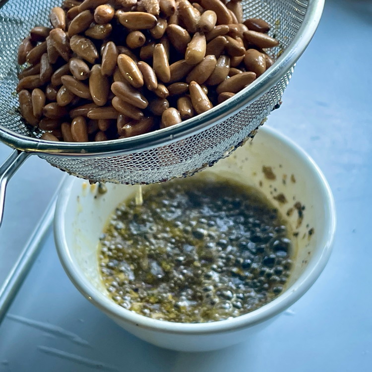 Image of Immediately strain the pine nuts - the hot oil will sizzle a bit as it toasts the Pasha.