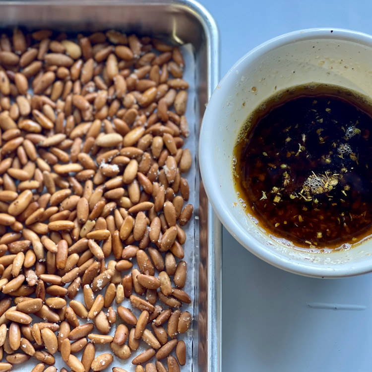 Image of Reserve the cooked pine nuts on a small rimmed baking sheet or plate. Allow the oil and pine nuts to cool completely. Once cool, combine the pine nuts and pasha flavored olive oil and spoon over anything!