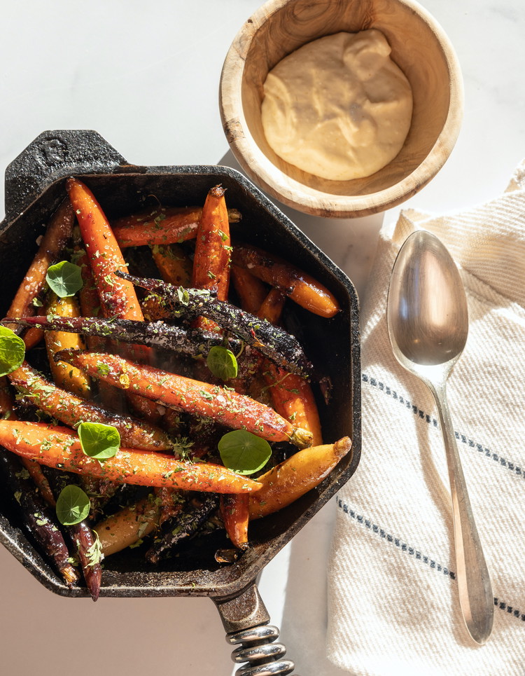 Image of When the carrots are fork-tender, remove from the oven and stir carefully to redistribute the glaze. Garnish with dried herbs, Upta Camp smoked sea salt, and cracked pepper. Serve in the cast iron with a few sprinkles of fresh green...