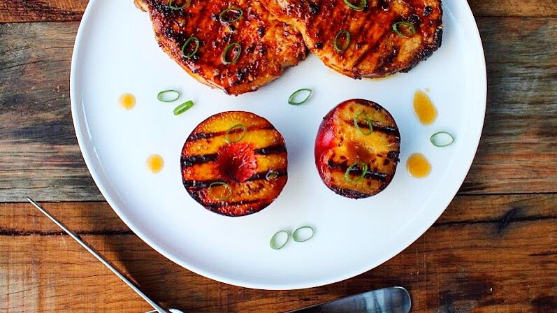 Image of SmokeyQ Chipotle Rub pork chops with a honey bourbon glaze and grilled fruit