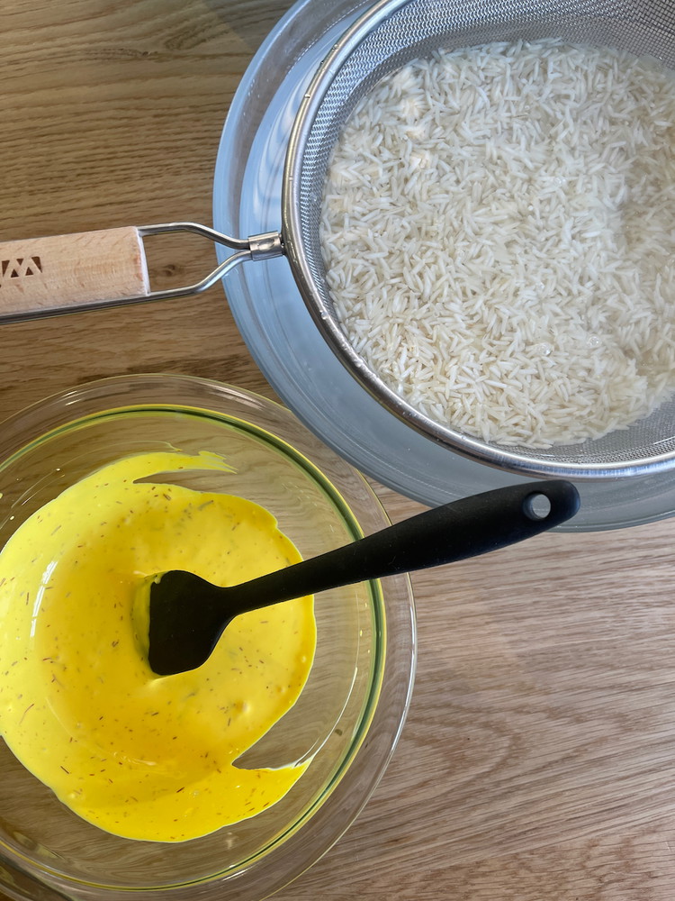 Image of In a small bowl, steep the saffron with hot water for 5 minutes, then add the labne to make a bright yellow mixture.