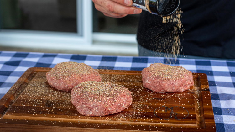 Image of Before you flip the burgers, season the top.  