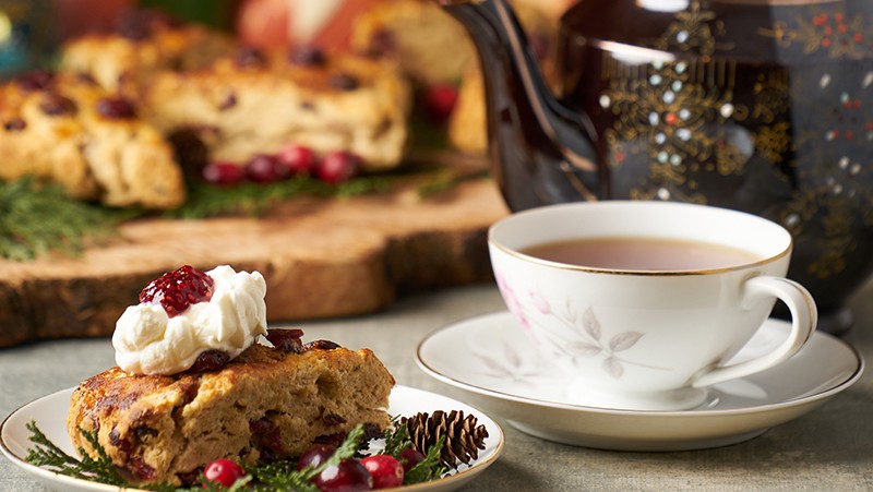 A plate with a scone and whipping cream. A tea cup with tea inside.