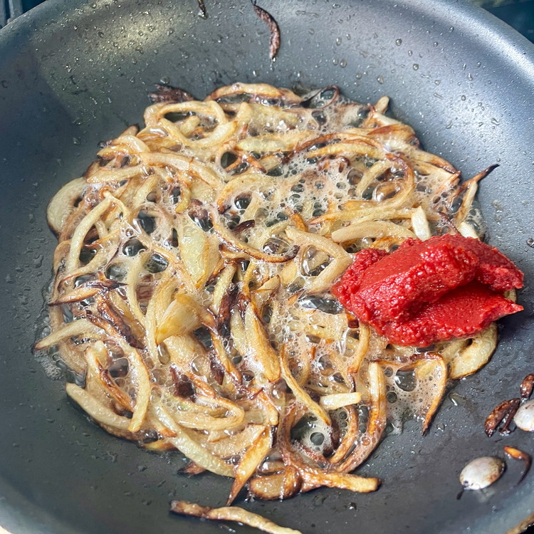 Image of When the sliced onion edges are browned, add the butter and continue cooking until well caramelized.  When ready, stir in the tomato paste to combine well.