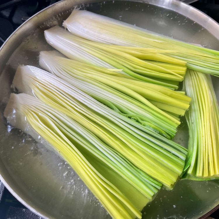 Image of Fill a skillet large enough to fit the leeks in a single layer with salted water and bring to boil.