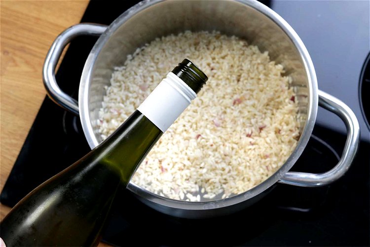 Image of Den Risotto-Reis dazugeben und anschließend mit einem Schluck Weißwein ablöschen.