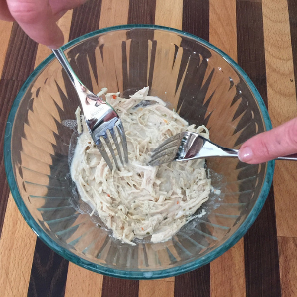 Image of Working one piece of chicken at a time, place chicken into a bowl and using two forks, shred the meat.  Place back in the slow cooker when finished.