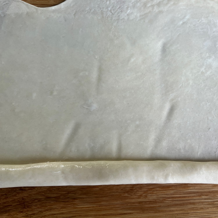 Image of Roll a ball of dough out into a paper thin (should be see-through) rectangle about 8”x12”.