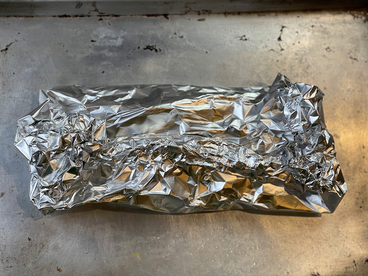 Image of Create a folded pouch with the carrots by raising the sides of the tin foil together and folding the ends. The objective here is to create an environment where the carrots can braise in the liquid.