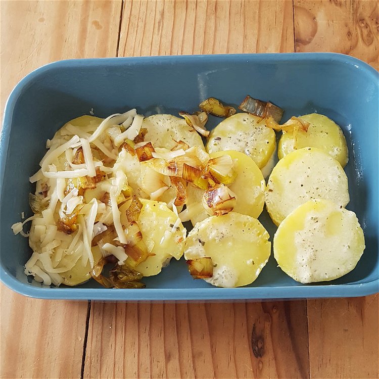 Image of Die gegarten Kartoffeln abwechselnd mit Lauch und Käse in eine...