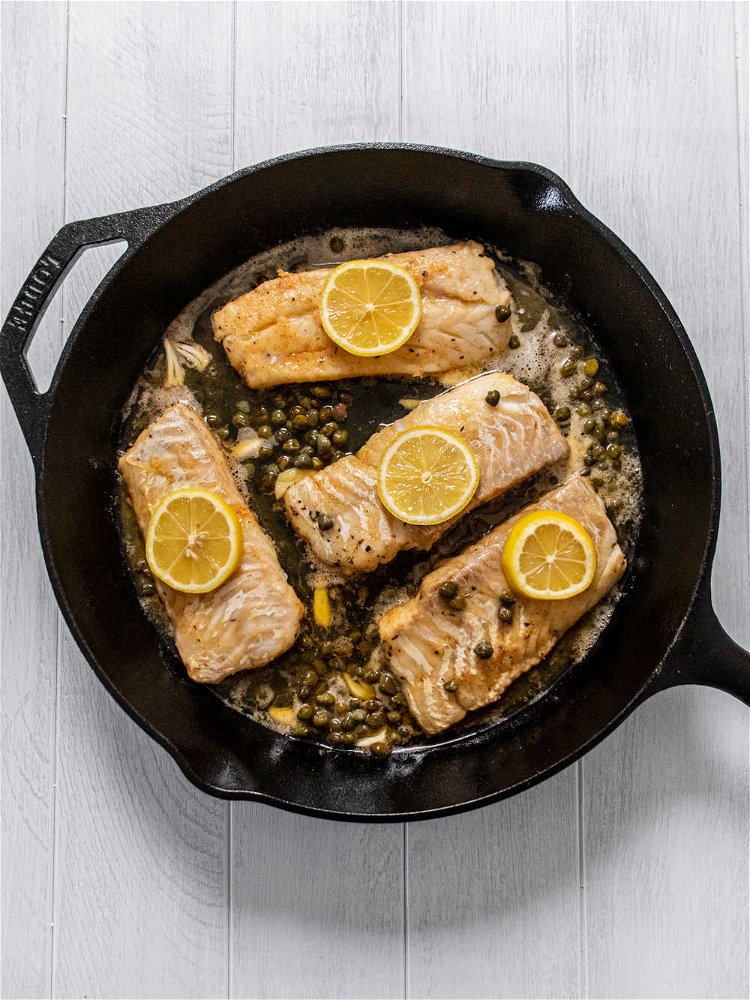 Image of Add sliced garlic, lemon slices and capers to skillet. Pour...