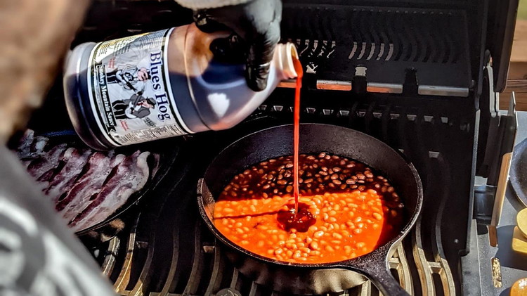 Image of Add beans to cast iron pot along with sliced jalapenos, Smokey Mountain BBQ Sauce, Blues Hog Original Dry Rub, and dijon mustard, giving a quick stir to blend everything together.