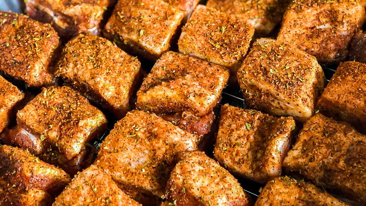 Image of Sprinkle sweet and savory seasoning on the pork belly, ensuring that all sides of the cubes are evenly coated.