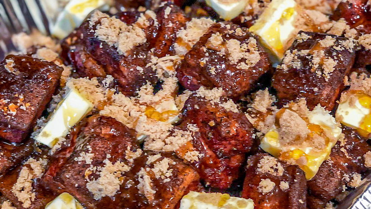 Image of Cover the pork belly cubes with slices from a stick of unsalted butter and top with brown sugar and honey. Cover the pan with aluminum foil and return to the smoker.