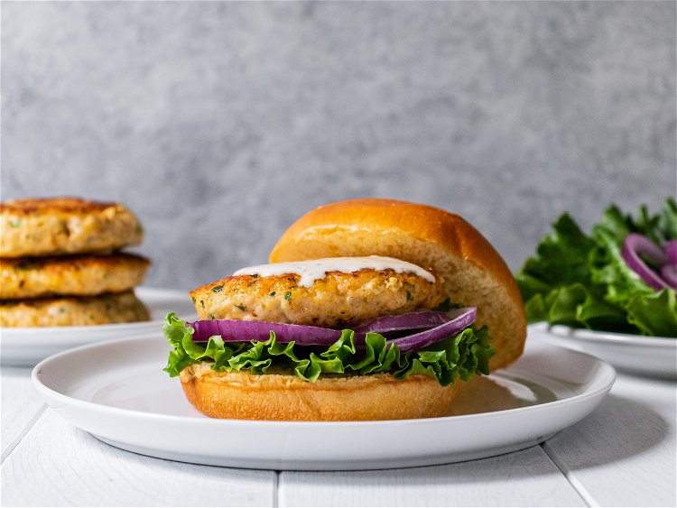 Image of Serve shrimp burgers on buns with lettuce, red onion, and...