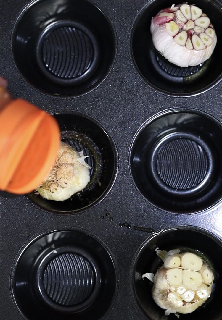 Image of Place the heads of garlic bread into your muffin tray. Drizzle olive oil on each head with a lashing of Oz Dirt seasoning for the ultimate flavour cheat code.