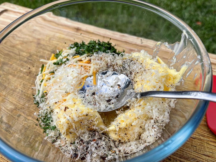 Image of Whilst the garlic is roasting away in your cooker of choice, in a bowl mix the butter, cheese, chilli flakes, salt, pepper, chicken salt and parsley until thoroughly blended.   