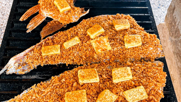 Image of Once pit is ready, place red fish skin down with a couple pads of butter.