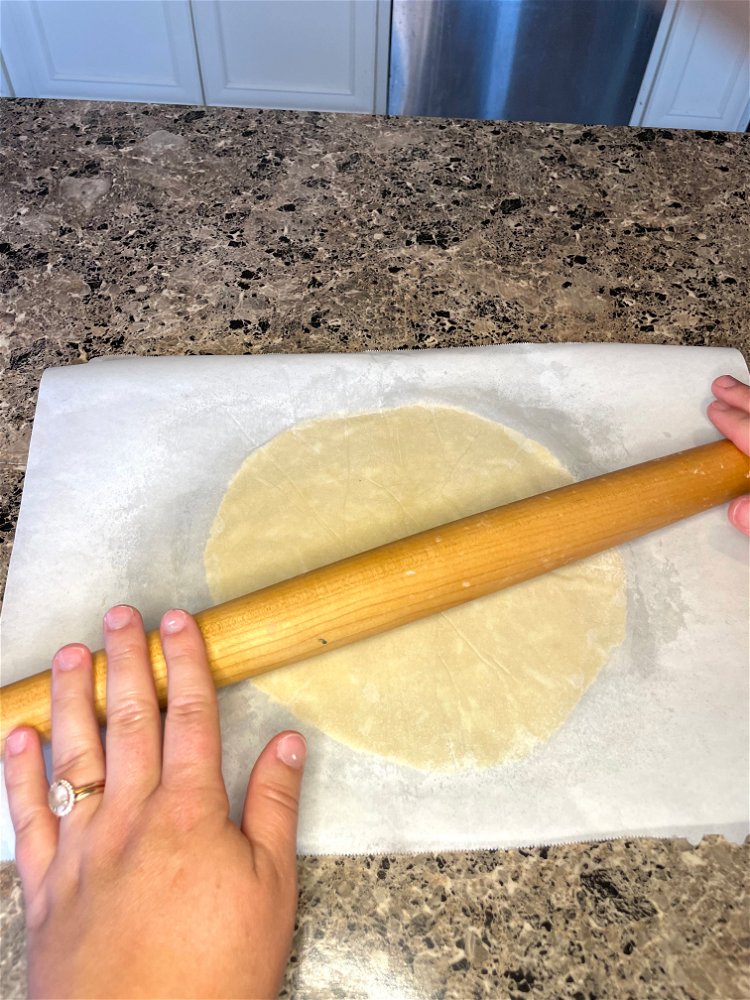 Image of Roll out each ball of dough between two sheets of...