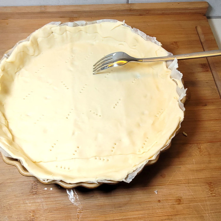 Image of Währenddessen den Teig in die Backform legen, mit einer Gabel den Teigboden einstechen