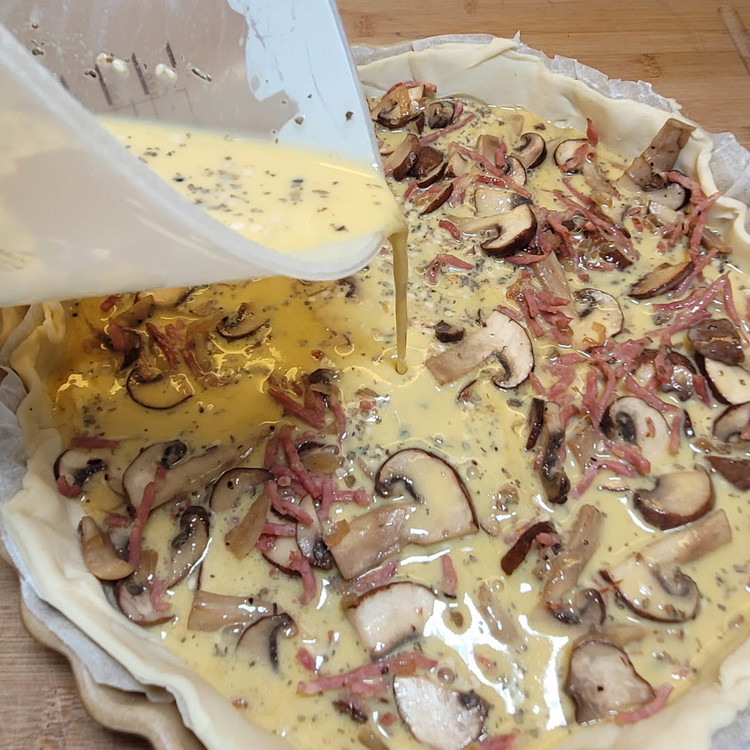 Image of Nun gibst du die Pilzfüllung auf den Teig und giesst den Guss dazu