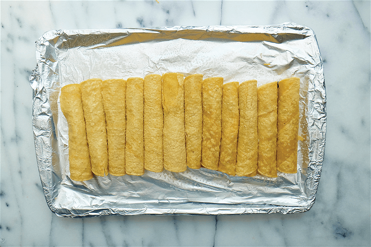 Image of Lightly brush the tops of the taquitos with oil (or...