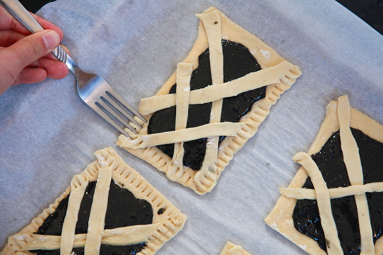 Image of Criss cross 3-4 dough strips over the filling so it forms a mummy wrap. Cut off any excess and use a fork to seal the edge. 
