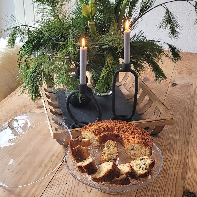Kuchenstücke auf einer Glasplatte vor Kerzen und Tannengrün