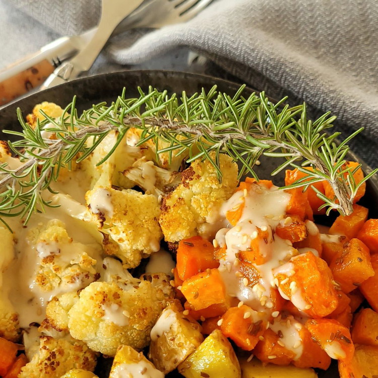 Image of Das Geröstete Gemüse hübsch auf Tellern anrichten. Mit den halbierten Datteln dekorieren und mit der Tahinisauce beträufeln.