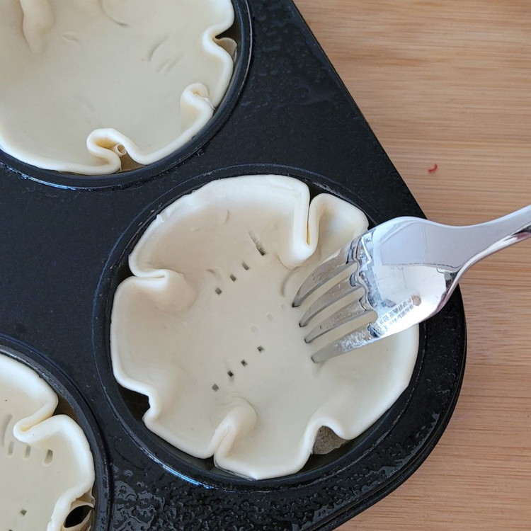 Image of Die ausgestochenen Blätterteigkreise in die Muffinform legen und mit einer Gabel einstechen