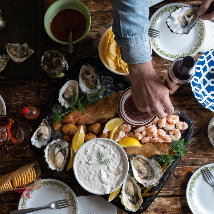 Image of Tuck in lemon wedges, mignonette, clam dip, and ritz crackers amongst the seafood.