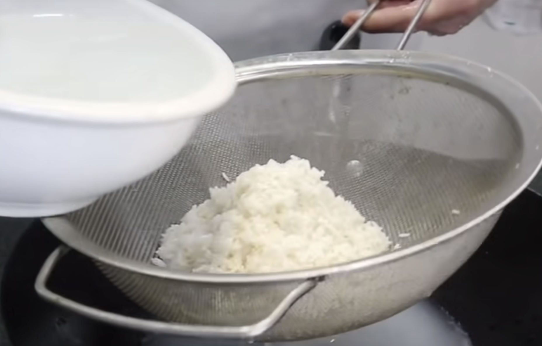 Image of Despeje o arroz embebido num filtro de malha para filtrar...