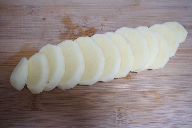Image of Descasque as batatas e corte em fatias grossas.