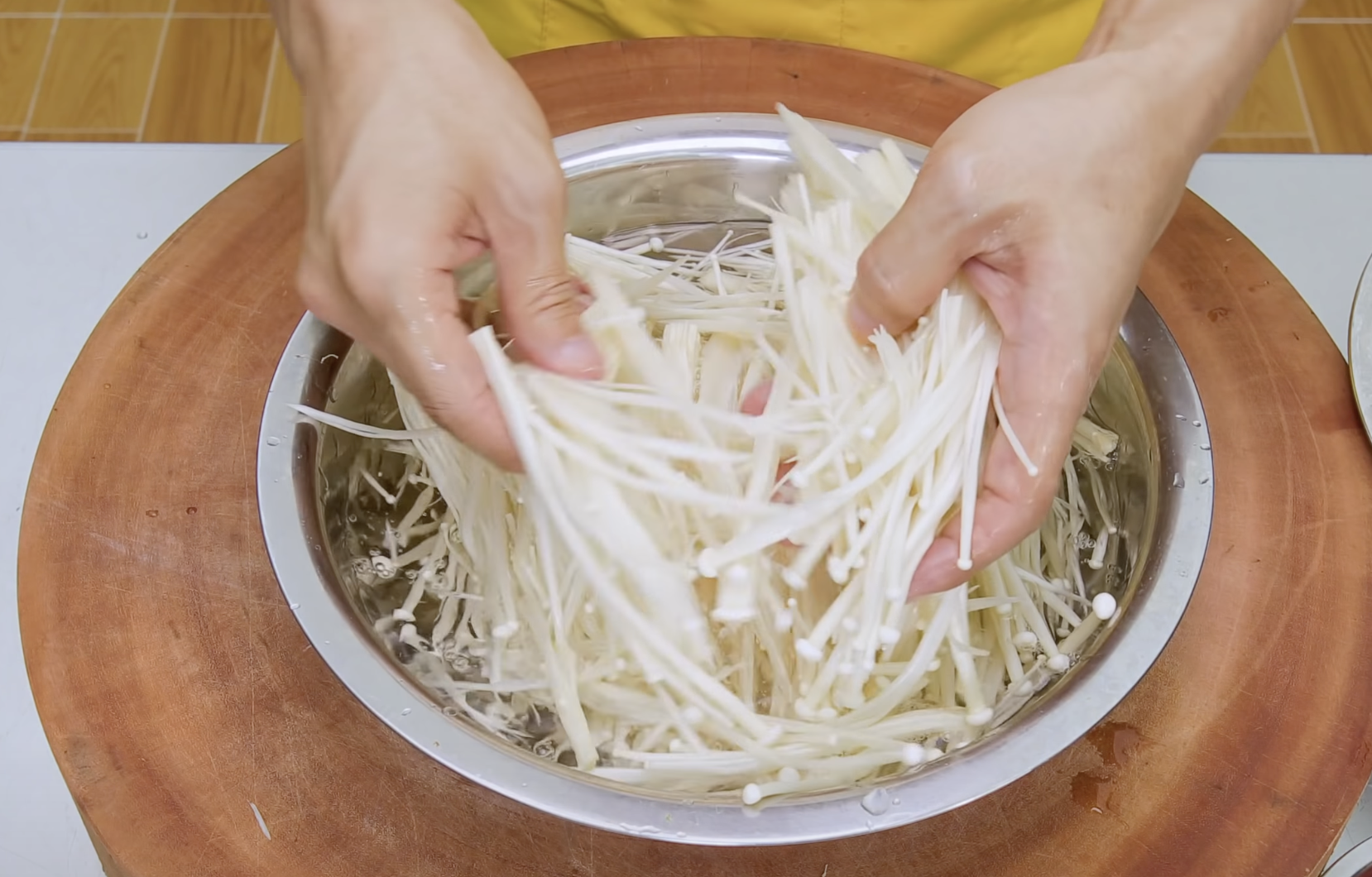 Image of Remova a raiz de Enokitake cogumelos, lave-a e rasgue-a uniformemente