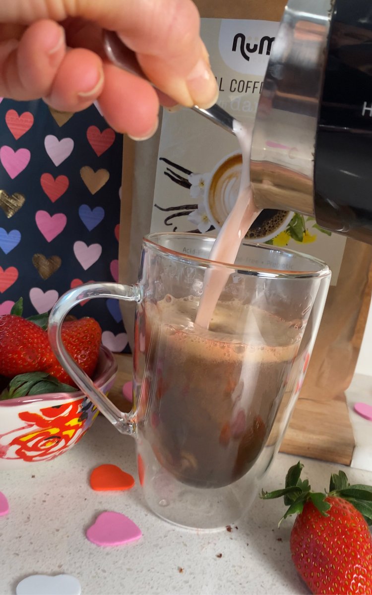 Image of Pour hot strawberry oat milk into latte, leaving a bit...