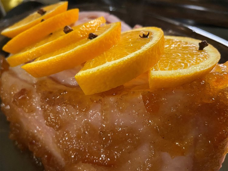 Image of Place orange slices on top of meat with a clove...