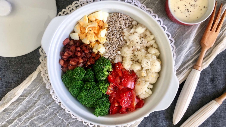 Image of  In a large bowl, combine broccoli, cauliflower, bacon bits, onion, tomatoes, eggs, and sunflower seeds. Optional: Blanch broccoli and cauliflower in boiling water for 2-3 minutes, then place in cold water.