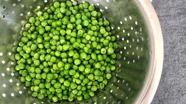 Image of Defrost frozen peas by placing them in a colander and running cold water until fully defrosted. Alternatively, put frozen peas in the refrigerator a day ahead of time.
