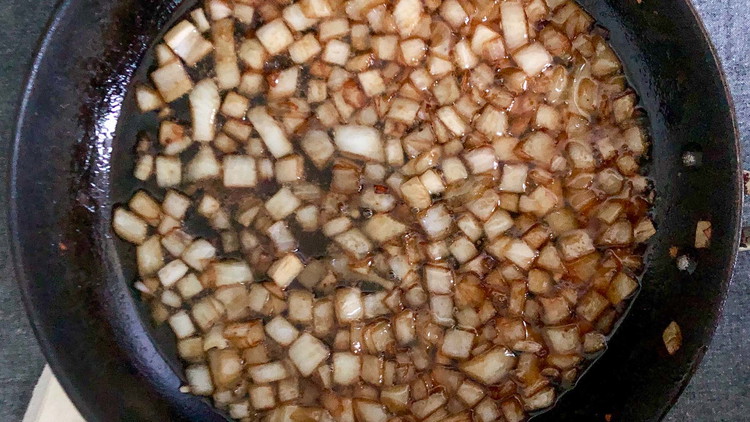 Image of Add onions to bacon grease and cook until browned on medium heat. Then add vinegar, sugar, and water and let reduce.