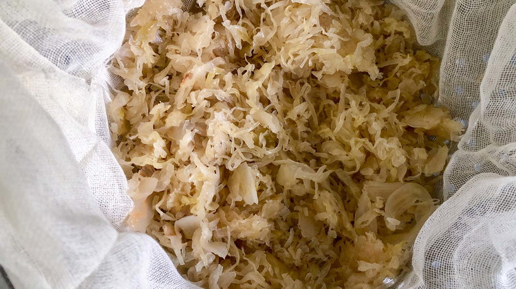 Image of Drain and rinse sauerkraut. Place cheesecloth in a colander and allow the sauerkraut to drain for 10 minutes. Remove any excess liquid by tightly squeezing the cheesecloth bundle or applying pressure with your hands.
