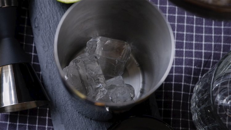Image of Nun wird der Limettensaft mit fünf Eiswürfeln in einen Shaker...